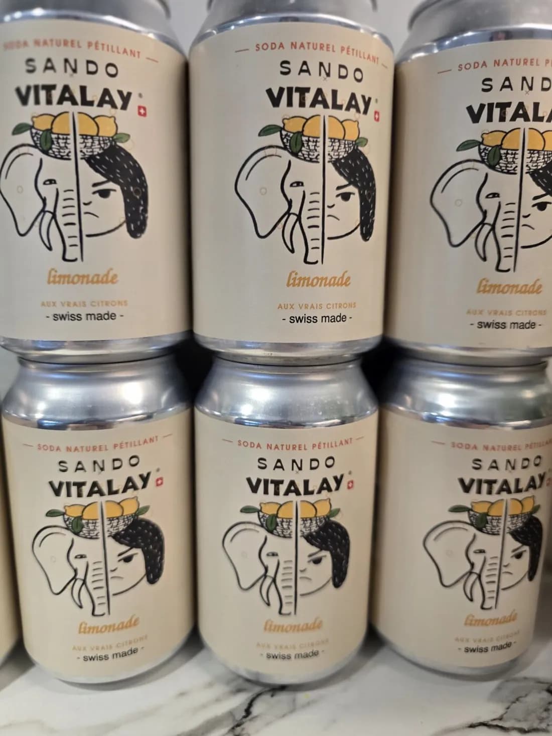 Stacked SANDO × VITALAY cans on a marble counter