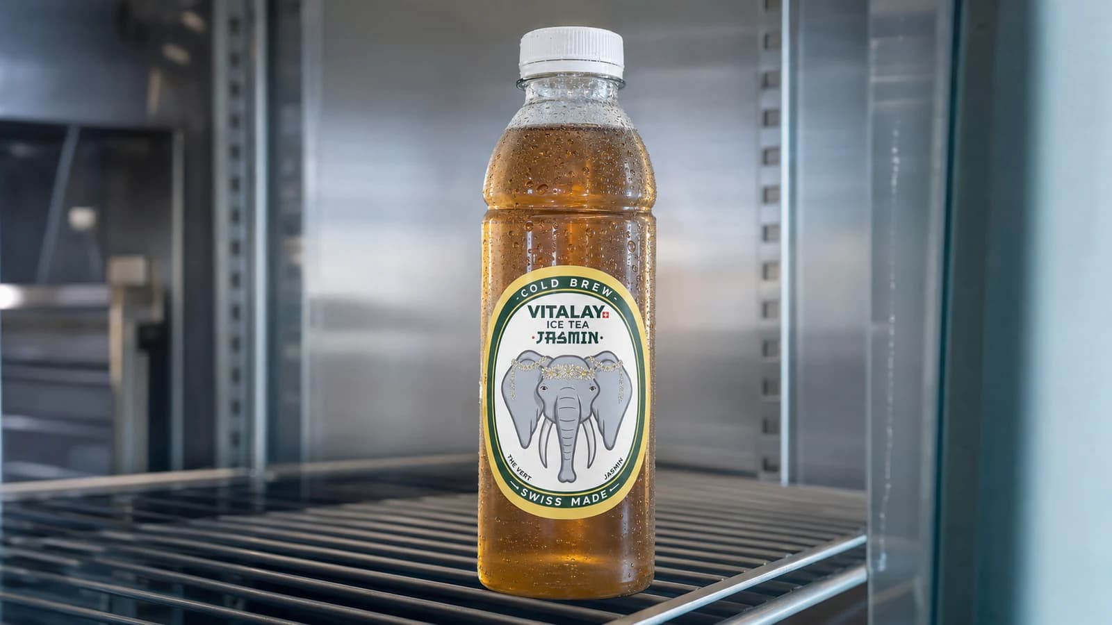 Bouteilles Vitalay alignées dans un réfrigérateur d'atelier en inox, lumière intérieure froide, condensation sur les bouchons